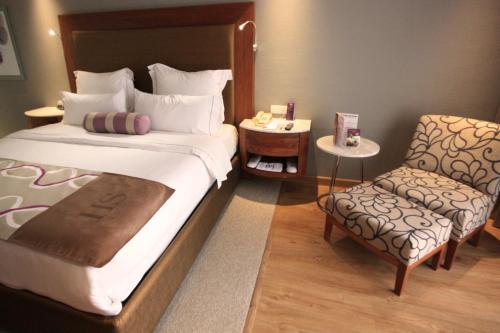 a bedroom with a large bed and a chair at HS HOTSSON Hotel Silao in Silao