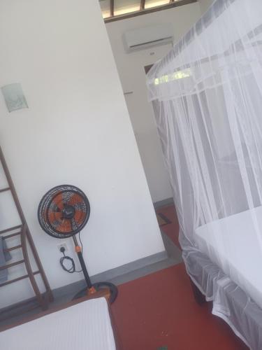 a room with a bed and a fan next to a window at Sunhill Rest Hiriketiya in Dickwella