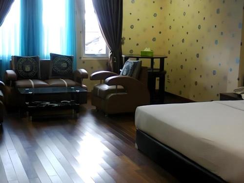a bedroom with a bed and a chair and a couch at Permata Hotel in Purwakarta