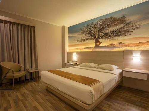 a bedroom with a large bed with a painting on the wall at Star Hotel in Pontianak
