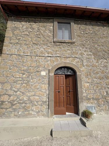 a stone building with a brown door and a window at Le coste sul lago in Montefiascone