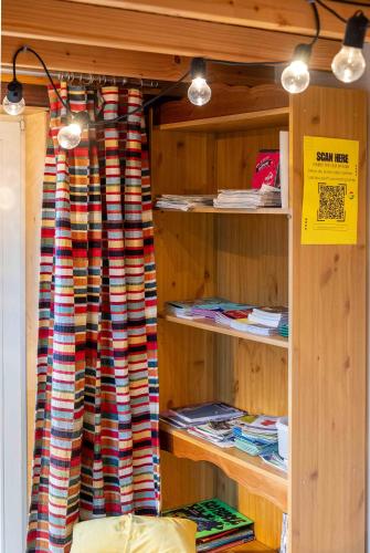 a room with a book shelf with a curtain at Tiny House Les Jours Heureux Sejour nature pres de Dinant et des Lacs de l Eau d Heure in Villers-le-Gambon