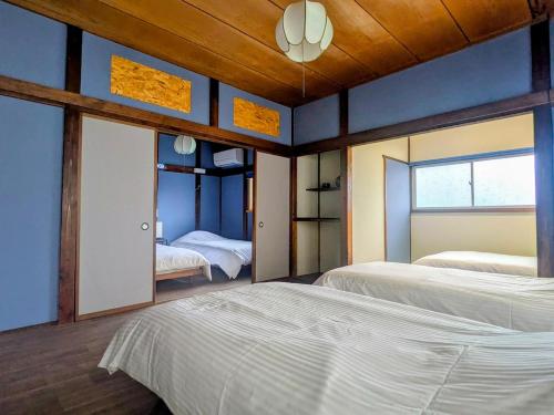 a bedroom with two beds and a blue wall at サマサマアイル saMa-saMa Aisle in Odawara