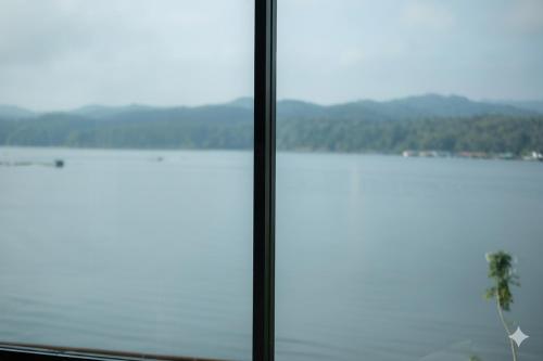 een raam met uitzicht op het water bij Phornpailin Riverside Resort in Sangkhla Buri