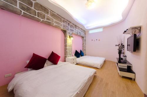 a bedroom with two beds and a pink wall at Shu Lan Yang Ye in Manzhou