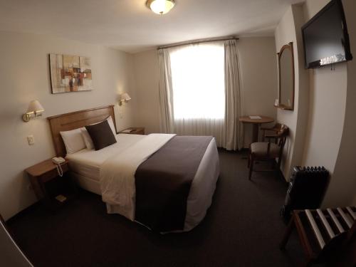 a hotel room with a bed and a television at Casona Plaza Hotel Puno in Puno