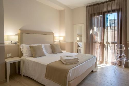 a white bedroom with a large bed and a window at Eunice Bed and Breakfast in San Vito lo Capo