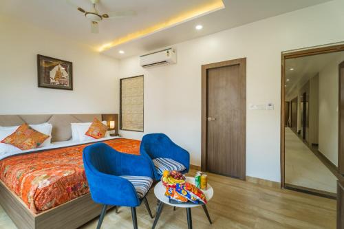 a bedroom with a bed and two blue chairs at Tripli Hotels Sandalwood in Varanasi