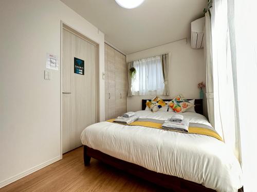 a bedroom with a bed with white sheets and a window at nestay villa tokyo oyama in Tokyo