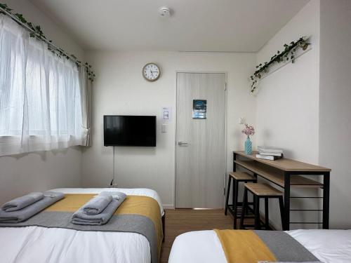 1 dormitorio con 2 camas, escritorio y TV en nestay villa tokyo oyama, en Tokio
