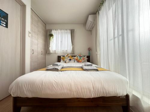 a bedroom with a bed with white sheets and a window at nestay villa tokyo oyama in Tokyo