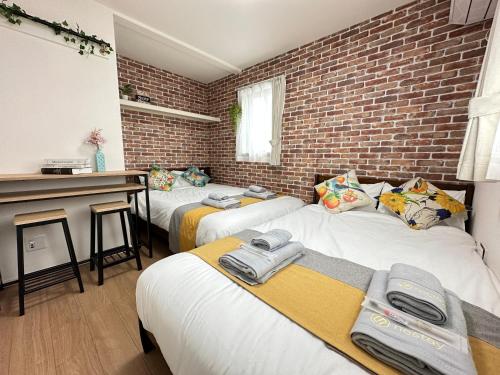 a room with three beds and a brick wall at nestay villa tokyo oyama in Tokyo