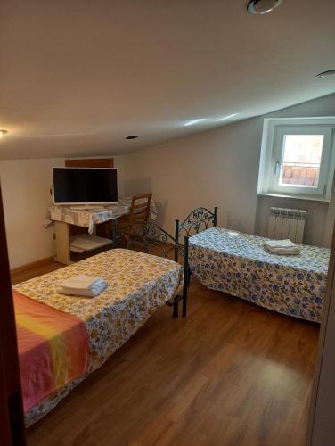 a room with two beds and a flat screen tv at Mansarda Casalina in Casole Bruzio