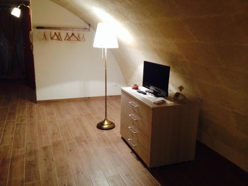 a room with a lamp and a dresser with a television at Le due arcate in Matera