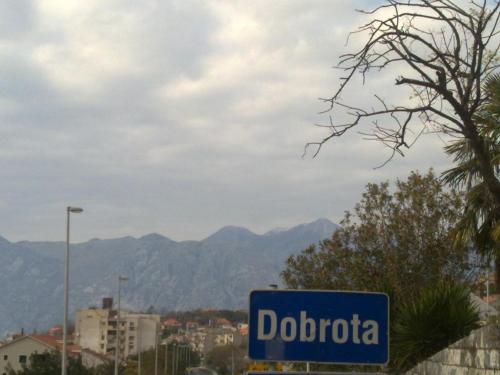 a blue street sign with mountains in the background at Panonija in Kotor