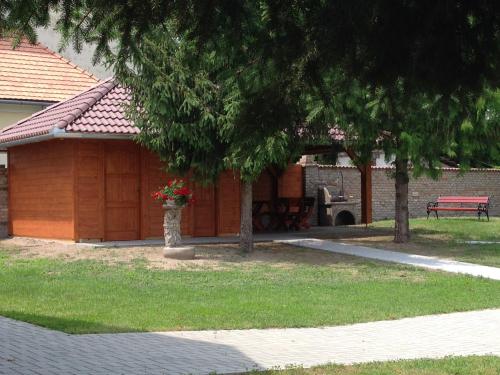a park with a building and a bench and trees at Althaus Vendégház in Németkér
