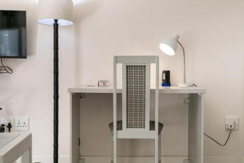 a desk with a lamp and a table with a mirror at Emmarentia Guest House in Johannesburg