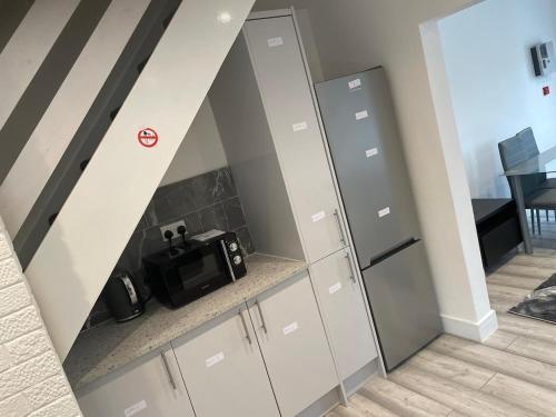 eine Küche mit weißen Schränken und einer Mikrowelle in der Unterkunft Limestreet place of harbour for contractors Crewe in Crewe