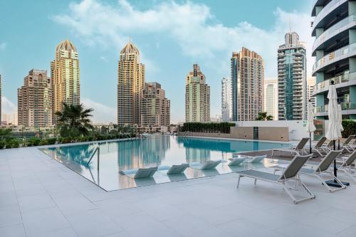 a swimming pool with chairs and a city skyline at Marina Horizon by LIV High Floor 1BR, For 5 Guests, Dual Gyms & Marina View in Dubai