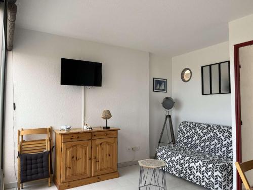 Appartement 2 pièces cabine 6 couchages PORT LEUCATE NATURISME PL080-TB21 في بورت لوكات: غرفة معيشة مع أريكة وتلفزيون على الحائط