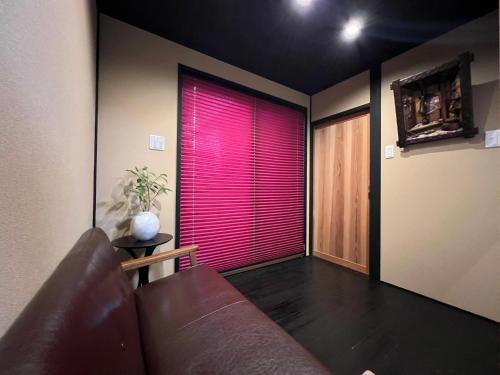 a living room with a couch and a window with pink blinds at 1-minute walk to Keihan Fushi mi Inari St ation 5-minute walk to Fushi mi Inari T aisha in Kyoto