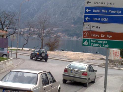 two cars driving down a road with a sign at Panonija in Kotor