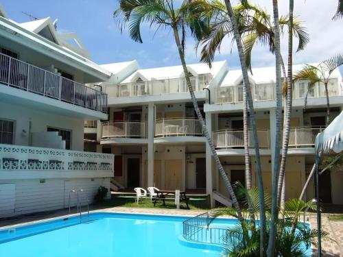 an apartment building with a swimming pool and palm trees at Petit Hotel Key West Club in Naha
