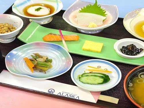 a table with plates of food and bowls of food at Hotel Abest Aomori in Aomori