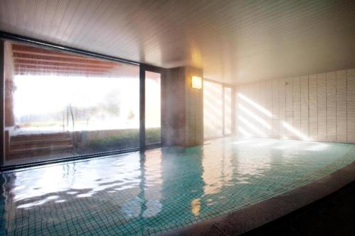 ein Schwimmbad in einem Gebäude mit einem großen Fenster in der Unterkunft Tateshina Wan-Wan Paradise Cottage in Tateshina