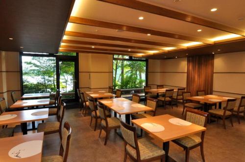 ein Restaurant mit Holztischen und -stühlen und Fenstern in der Unterkunft Tateshina Wan-Wan Paradise Cottage in Tateshina