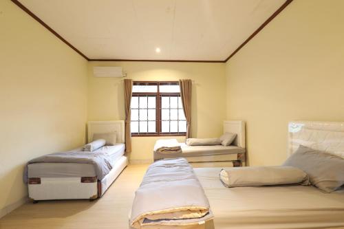 a room with two beds and a window at Imah Budi Luhur in Bandung