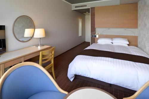 尾道市にあるGreen Hill Hotel Onomichiの大きなベッドと机があるホテルの部屋