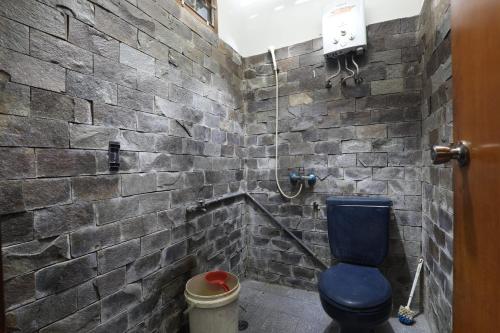 a bathroom with a blue toilet and a stone wall at Imah Budi Luhur in Bandung