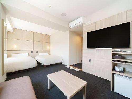 a hotel room with two beds and a flat screen tv at Super Hotel Satsuma Sendai in Satsumasendai