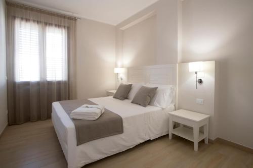 a white bedroom with a large bed and a window at Nesea Bed and Breakfast in San Vito lo Capo