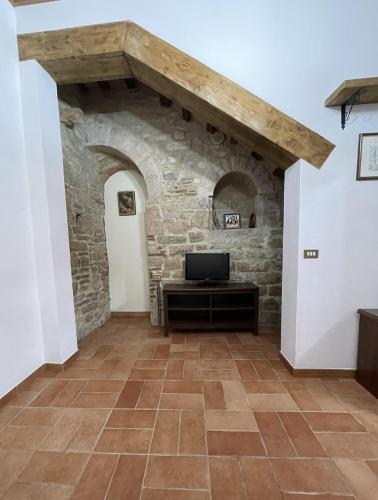 a living room with a stone wall and a television at Appartamento Barone in Gubbio
