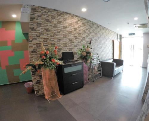 ein Büro mit einer Ziegelwand und einem Schreibtisch mit Blumen in der Unterkunft Hotel Bestari Prima in Kuala Lipis