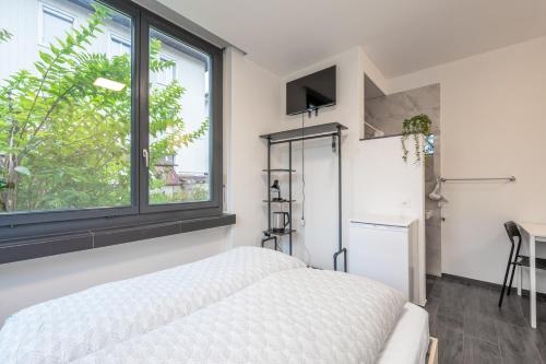 a bedroom with a white bed and a window at Mount Pilatus Rooms Lucerne in Luzern