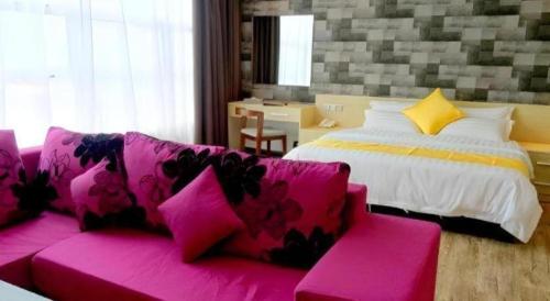 a pink couch in a room with a bed at Kidurong Inn in Bintulu
