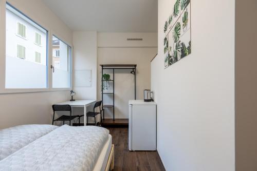 a bedroom with a bed and a desk and a window at Mount Pilatus Rooms Lucerne in Lucerne