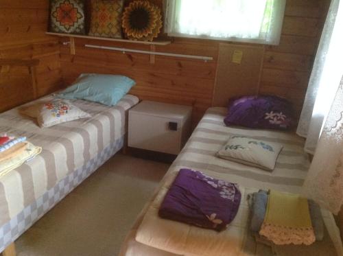 2 camas en una habitación pequeña con almohadas moradas en Holiday Home Victoria, en Svartbäck