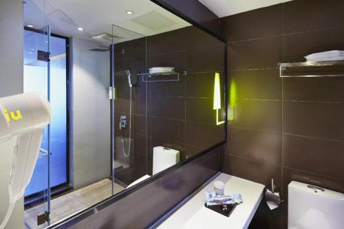 ein Badezimmer mit Dusche, Waschbecken und Spiegel in der Unterkunft IU Hotels·Xinyu City Government Xianlai Park in Xinyu