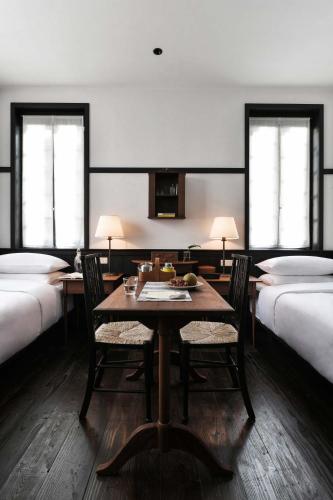 a room with a table and chairs and two beds at Gulangyu HUMBLE HALL Resort Hotel - Century-Old Historic Building & Banyan Courtyard - Near Sunlight Rock - Free Handmade Afternoon Tea & Breakfast - Pier Luggage Service - Free Island Walking guide & Hidden Route Guide - Paid English Tour Guide Service in Xiamen