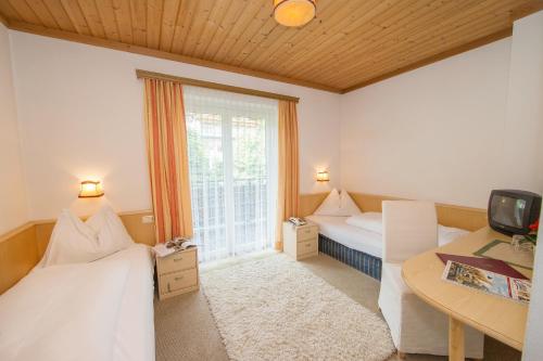 a room with two beds and a desk and a window at Pension Margarete in Zell am See