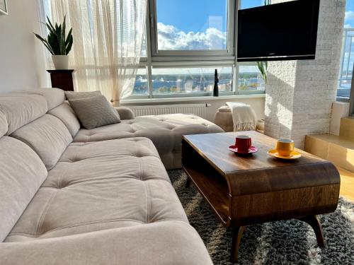 a living room with two couches and a flat screen tv at Panoramic sea-view penthouse in Klaipėda