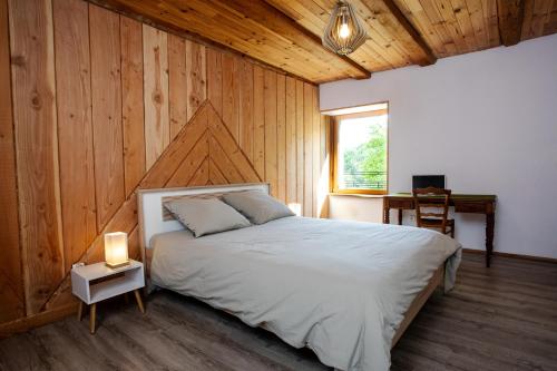 a bedroom with a bed with a wooden wall at Domaine Jurassic Farm in Moirans-en-Montagne