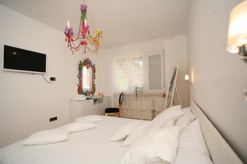 Habitación blanca con cama y lámpara de araña. en Domus Apartments en Trogir