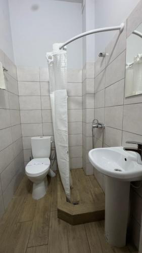 a white bathroom with a toilet and a sink at Міні-готель "ЕКО" in Kamianets-Podilskyi