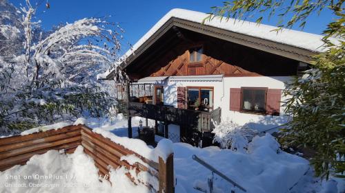 a house covered in snow with a balcony at Ferienapartment Opitz - Zugspitzregion in Ohlstadt