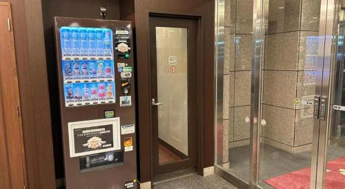 弘前市にあるHotel Route Inn Hirosaki Ekimaeのドアの横にある水のボトルが入った自動販売機